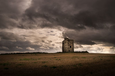 Built structure on field against cloudy sky