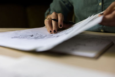 Cropped image of woman writing in book at table