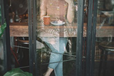Low section of woman seen through glass window