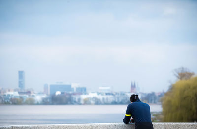 Rear view of man looking at sea against sky