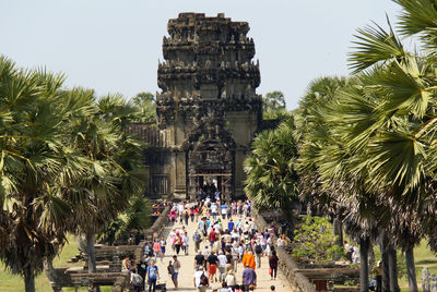 People outside temple against sky