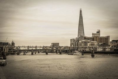 View of buildings at waterfront against cloudy sky