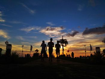 Silhouette people walking against sky during sunset