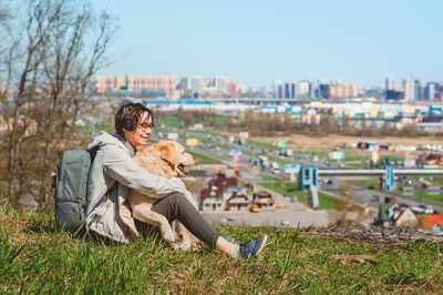 Woman with dog sitting on land