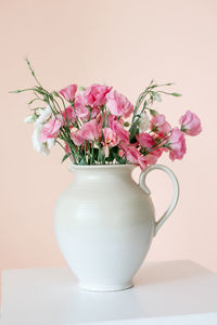 Close-up of pink flower vase on table against wall