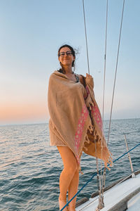 Woman standing by boat in sea against sky