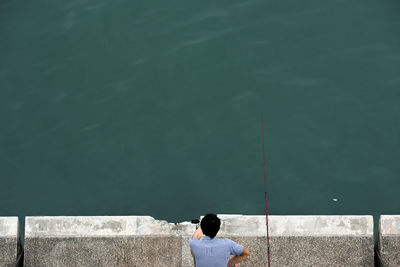 Rear view of woman standing by lake