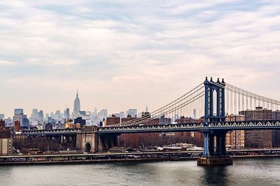 Bridge over river against cloudy sky