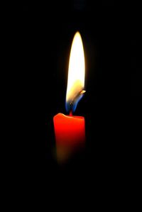 Close-up of lit candle in darkroom