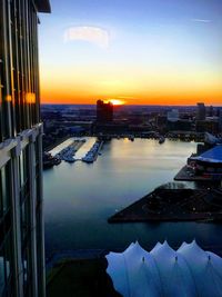 Scenic view of river and buildings against sky during sunset