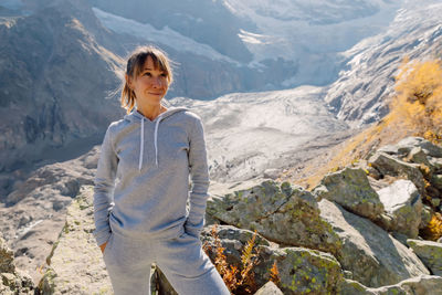 Portrait of young woman standing against mountain