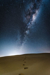Scenic view of desert against star field in sky at night