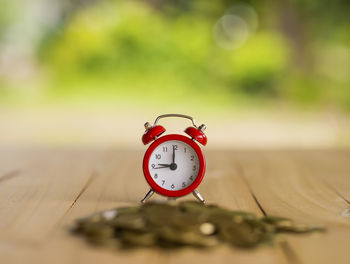 Alarm clock on coins on table