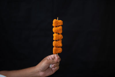 Close-up of hand holding ice cream against black background