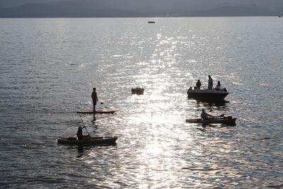 People in boat sailing on sea against sky