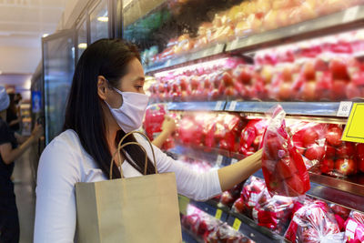 Woman holding apples while standing in supermarket