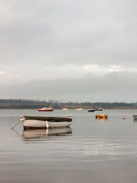 Sailboats moored on sea against sky