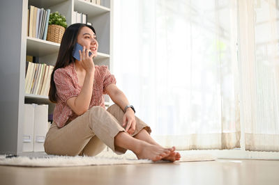 Young woman using phone while sitting at home