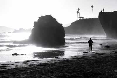 Silhouette woman standing at beach against sky