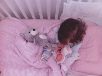 High angle view of girl with toys in crib