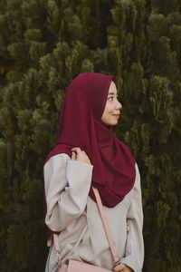 Woman in hijab standing against trees at park