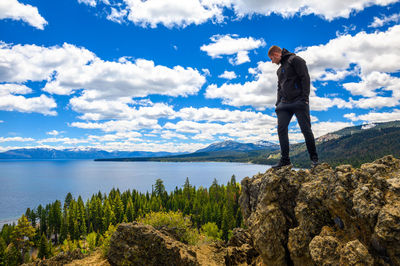 Rear view of man standing on rock against sky