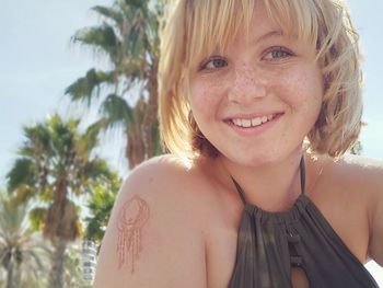 Portrait of smiling young woman against trees