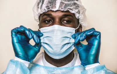 Doctor wearing mask sitting against colored background