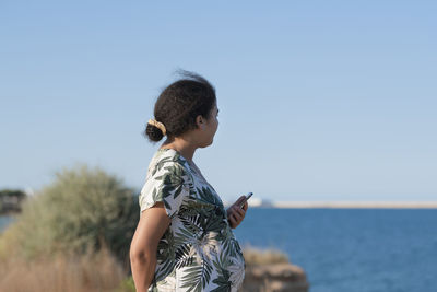 Side view of young man standing against sea