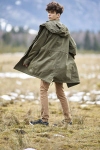 Portrait of young woman wearing coat standing on field