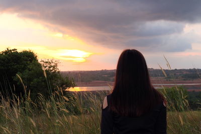 Rear view of woman against sky during sunset