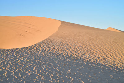 Scenic view of desert against clear blue sky