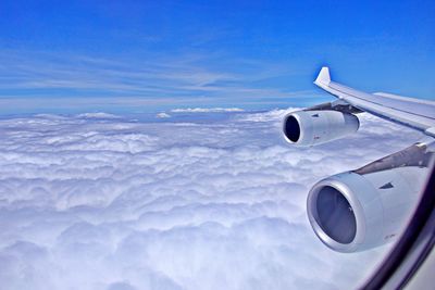 Airplane flying over cloudscape against blue sky