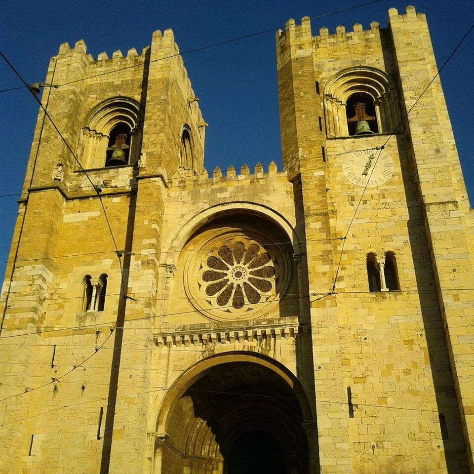 architecture, low angle view, built structure, building exterior, religion, church, arch, place of worship, spirituality, cross, sky, history, clock, facade, window, clear sky, cathedral, no people