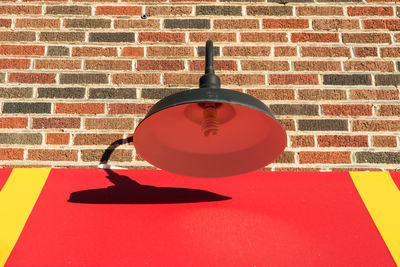 Electric lamp hanging against brick wall