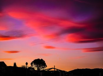 Low angle view of silhouette trees against orange sky