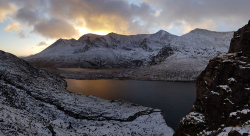 Scenic view of lake by mountains against sky during sunset