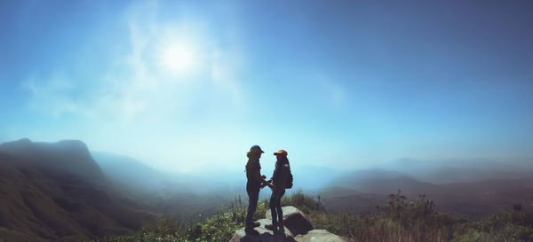 Rear view of man standing on mountain against sky