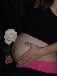 Midsection of woman holding rose at home