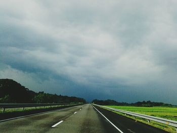 Country road against cloudy sky