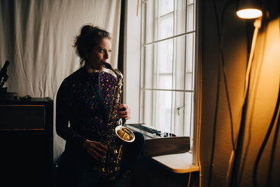 Young woman playing guitar at home