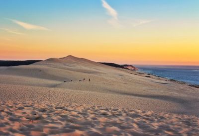 Scenic view of dune of pilat against sky at sunset