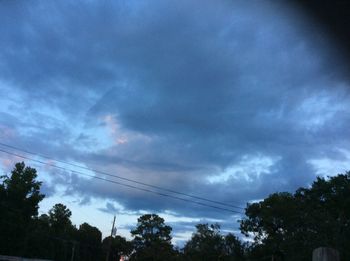 Low angle view of silhouette trees against cloudy sky