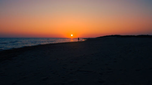 Scenic view of beach against clear sky during sunset