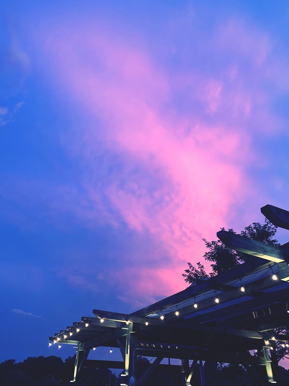 LOW ANGLE VIEW OF ILLUMINATED BUILDING AGAINST SKY AT NIGHT