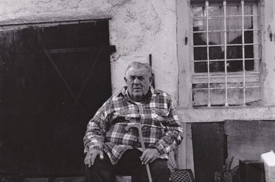Portrait of senior man sitting against old building