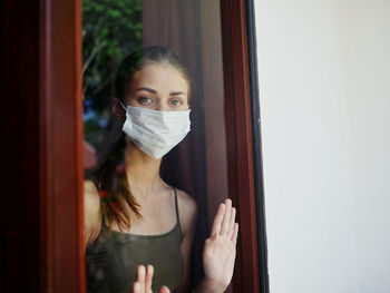 Portrait of young woman standing against door