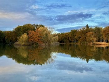 Scenic view of lake by trees against sky