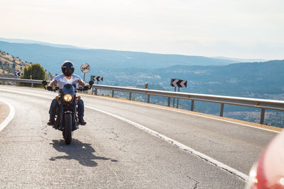 Young man riding motorcycle on road