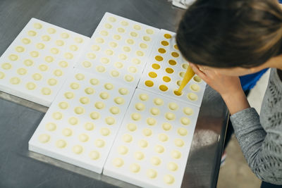 High angle view of chef filling molds while standing at table in chocolate factory